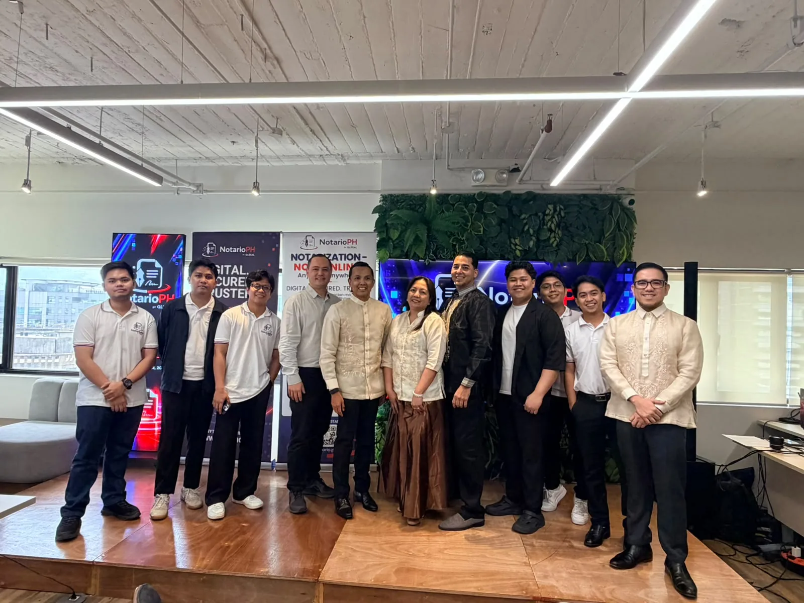 A larger group of launch participants posing on the event stage in front of NotarioPH screens and banners