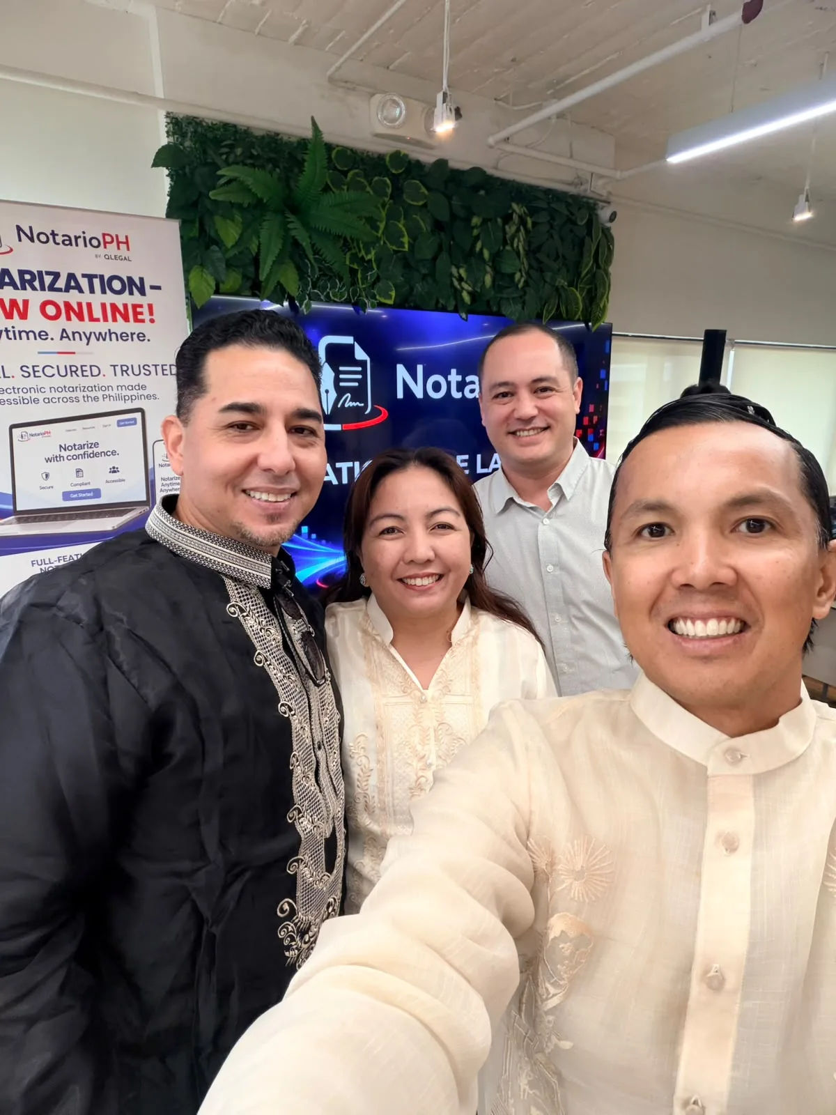 Four smiling guests taking a selfie in front of a NotarioPH banner at the launch venue